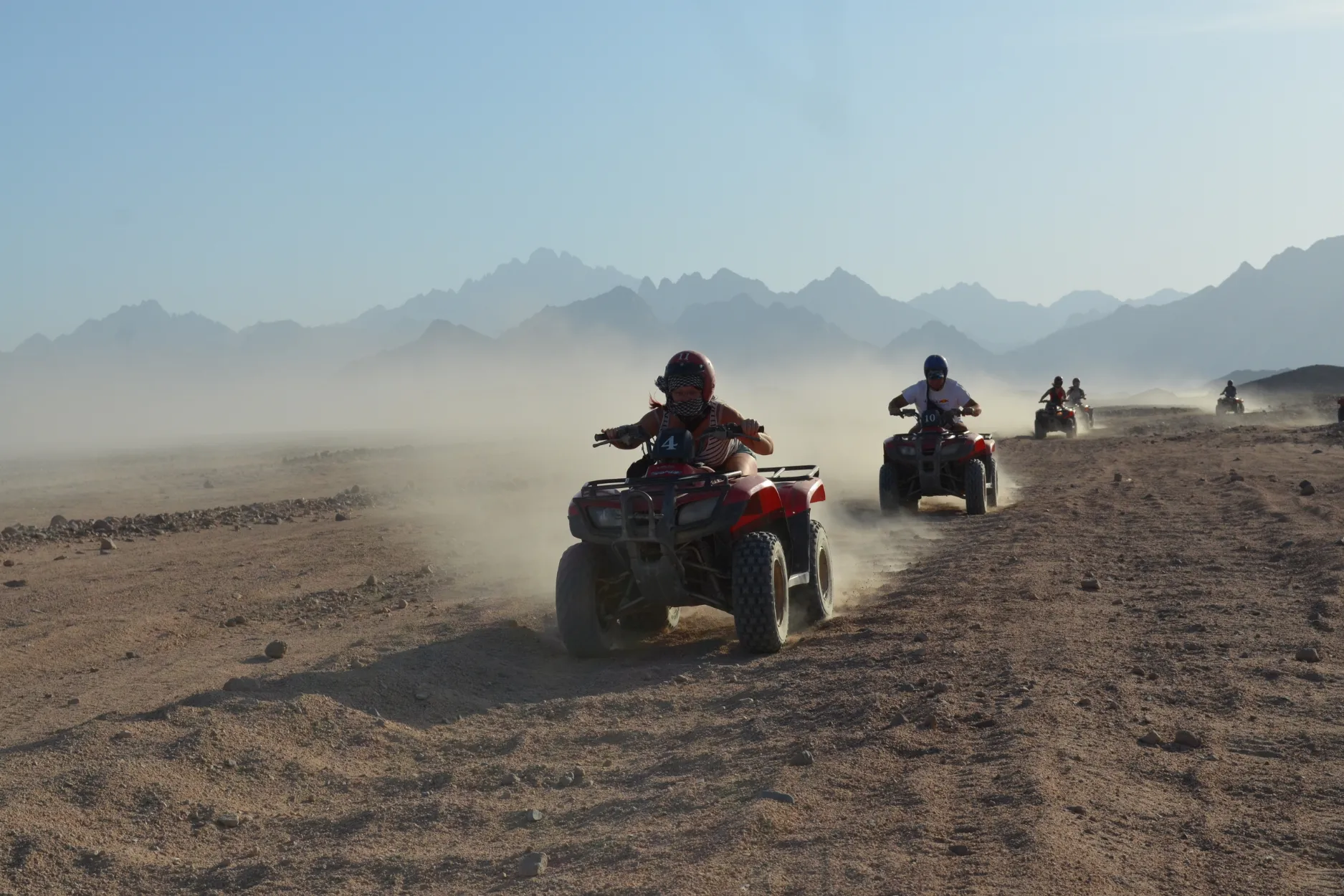 Deux quads sur une piste désertique avec des montagnes à l’arrière-plan