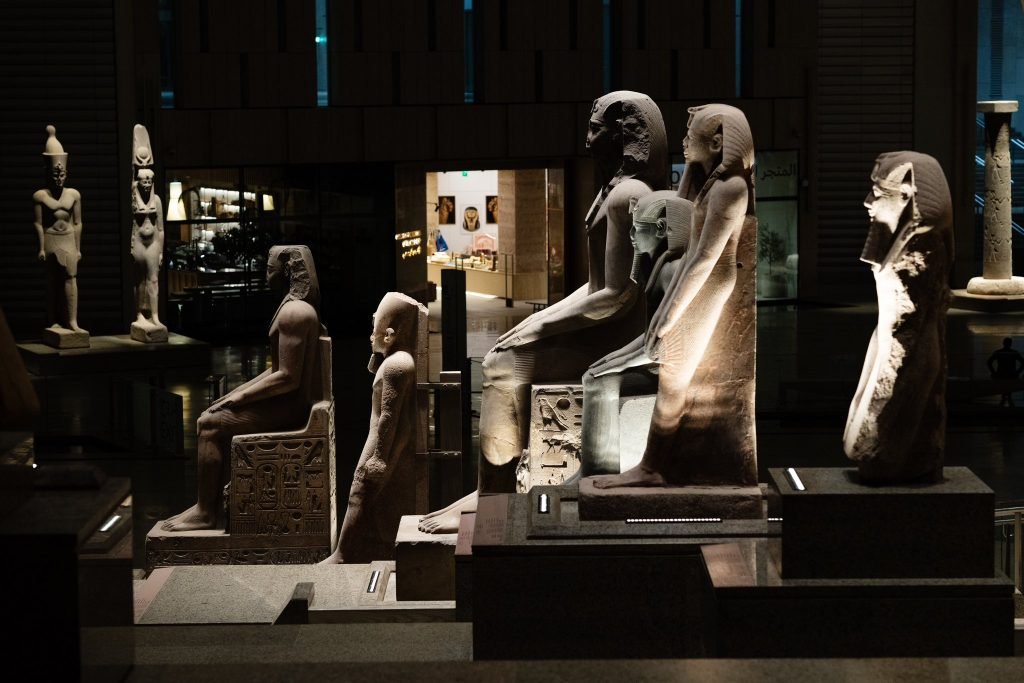 Reihe antiker ägyptischer Sitzstatuen in einer Museumsgalerie