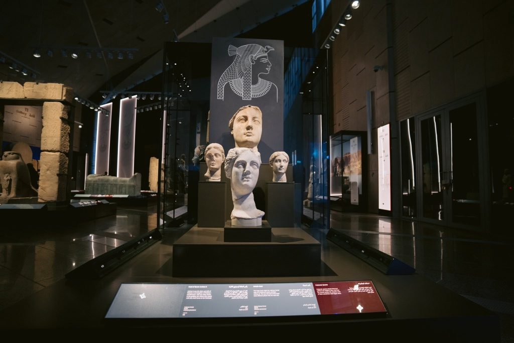 Ausstellung ägyptischer Skulpturen mit steinernen Köpfen und erläuternden Tafeln