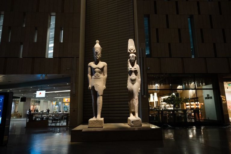 Zwei ägyptische Standfiguren unter hohen Wänden im Museumsinneren