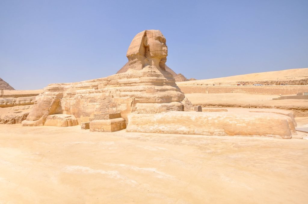 Die Große Sphinx von Giza vor dem sandfarbenen Gelände des Plateaus