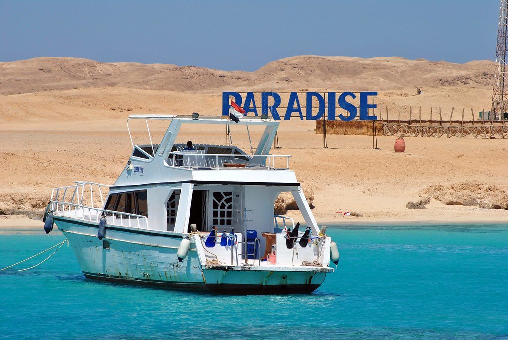 Bateau devant la plage et le panneau Paradise Island
