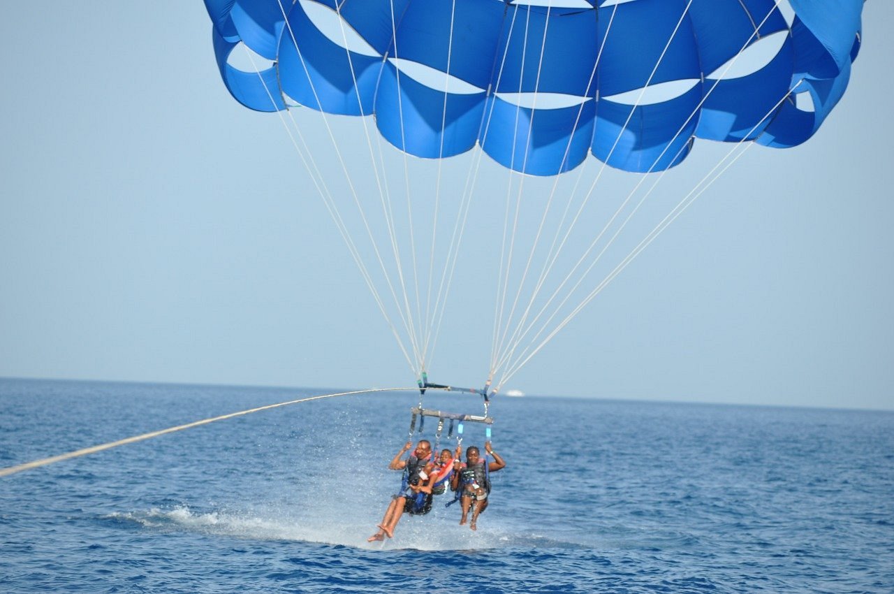 Trois participants sous une voile bleue au-dessus de la mer