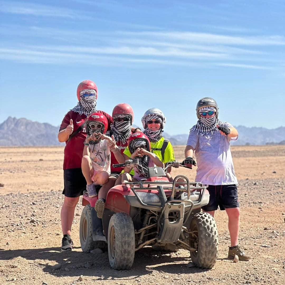 Familie mit Gesichtstüchern an einem Quad in der Wüste