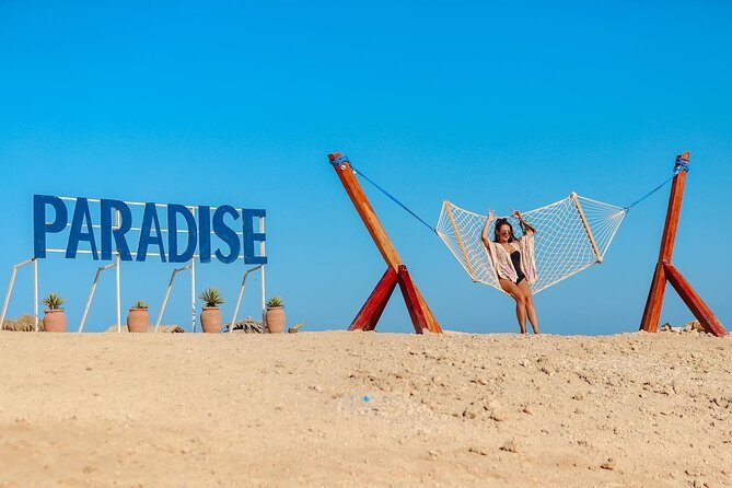 Paradise-Schriftzug und eine Hängematte am Sandstrand