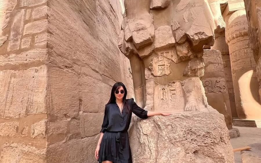Person neben einer monumentalen Statue im Karnak-Tempel