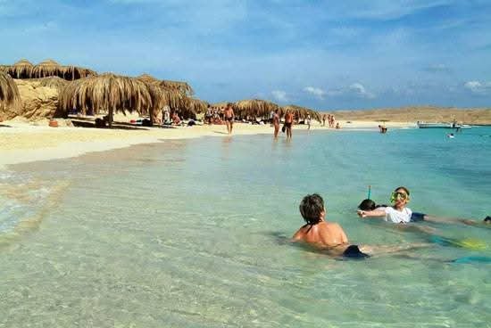 Voyageurs dans les eaux peu profondes près d’une plage aménagée