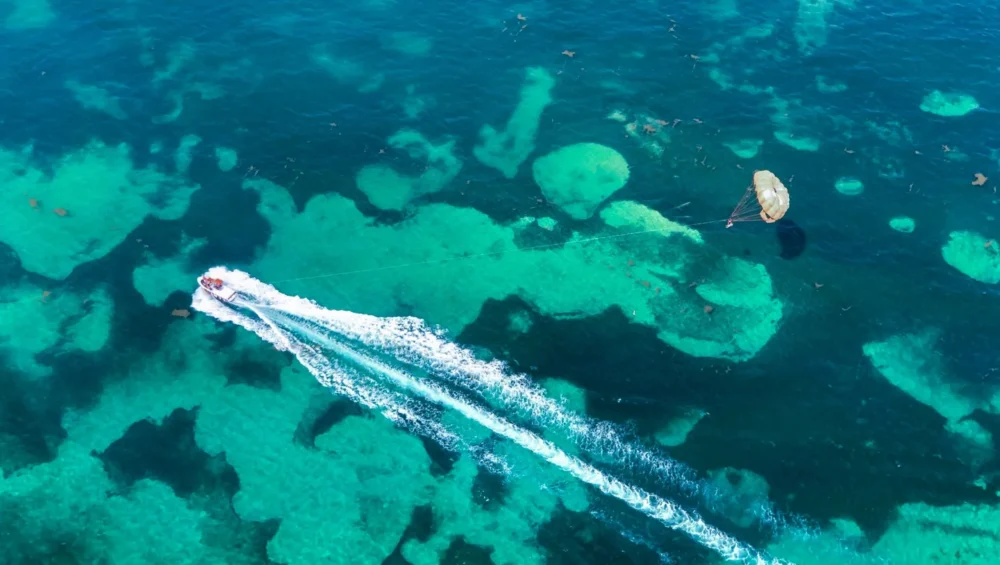 Aerial view of a motorboat towing a parasail over turquoise water