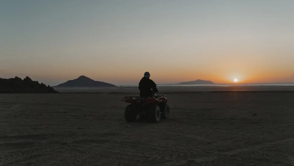 Rear view of a quad rider facing the setting sun