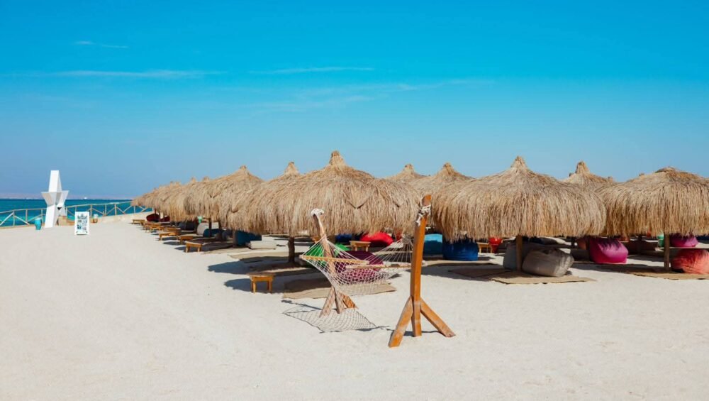 Sandy beach with thatched umbrellas beside turquoise water