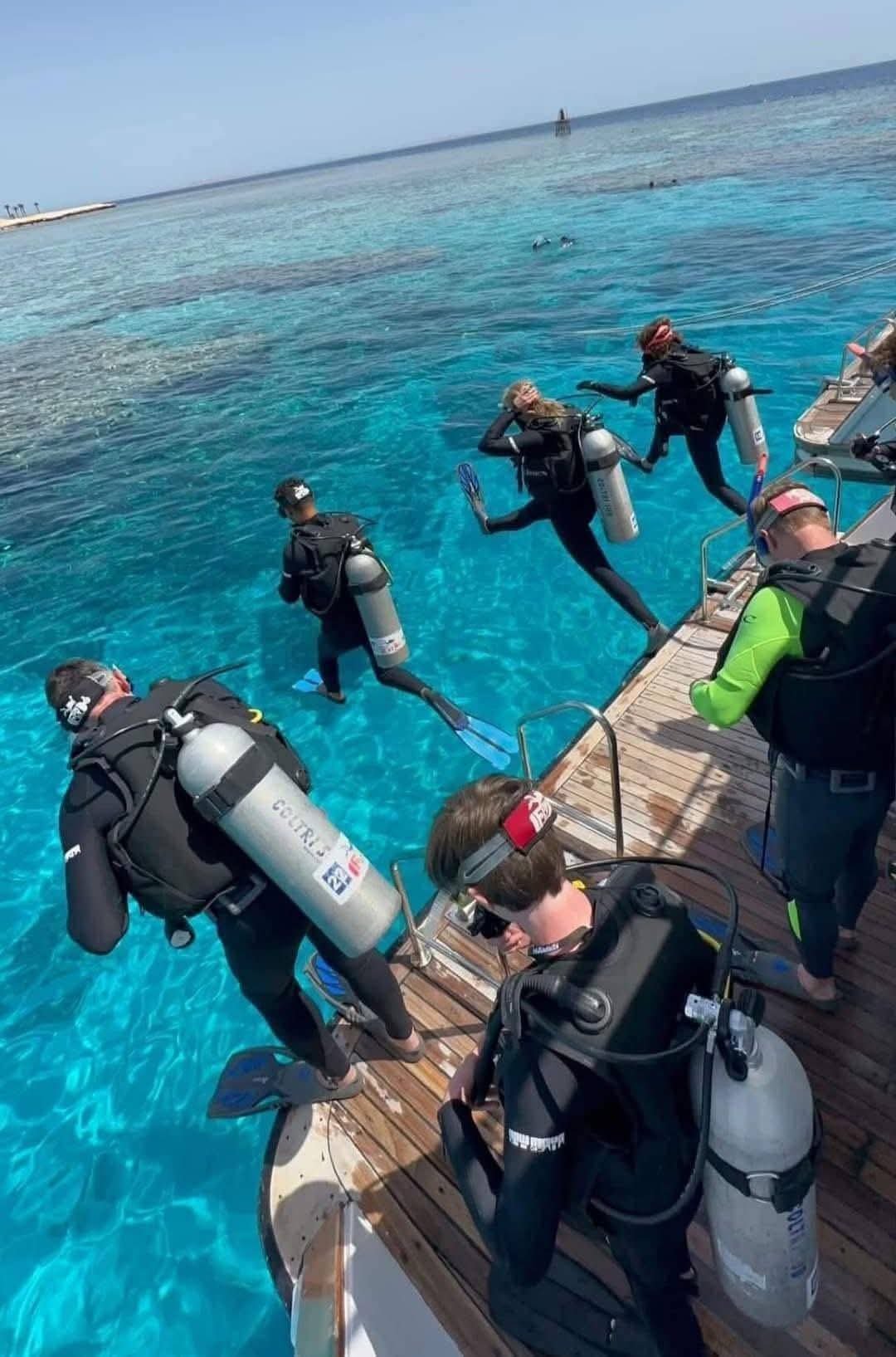 Scuba divers preparing to enter the water from a boat