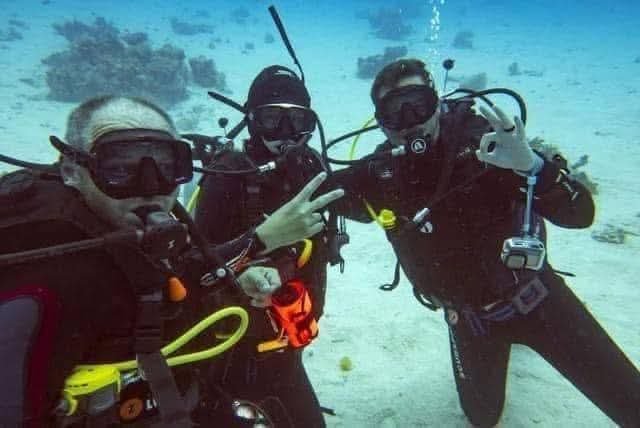 Group of scuba divers with masks and regulators underwater