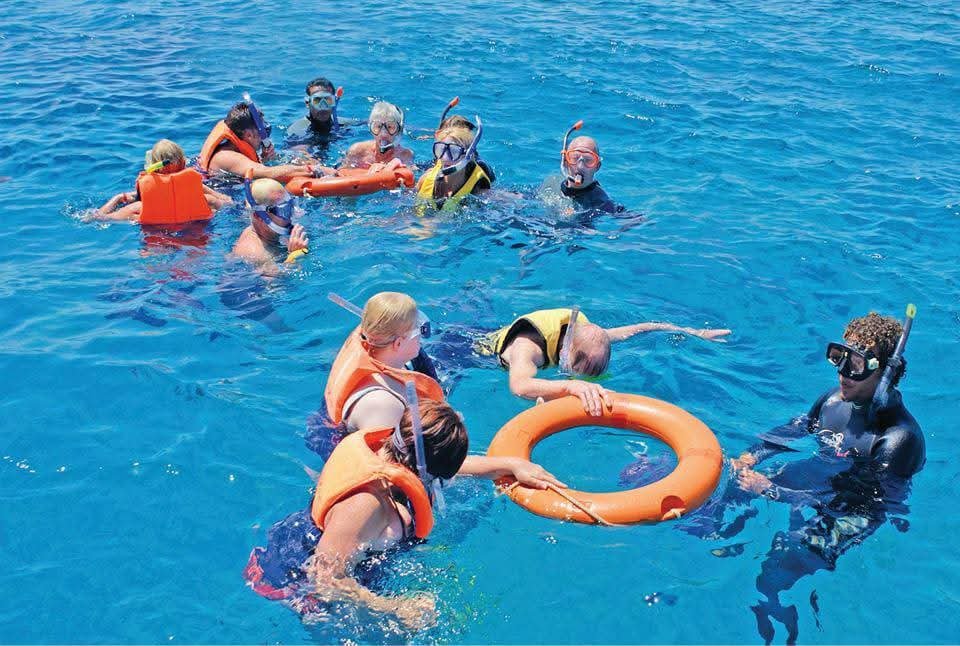 Snorkeling group using flotation rings in clear blue water