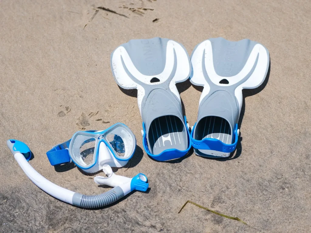Blaue und weiße Flossen mit Schnorchelmaske auf hellem Sand