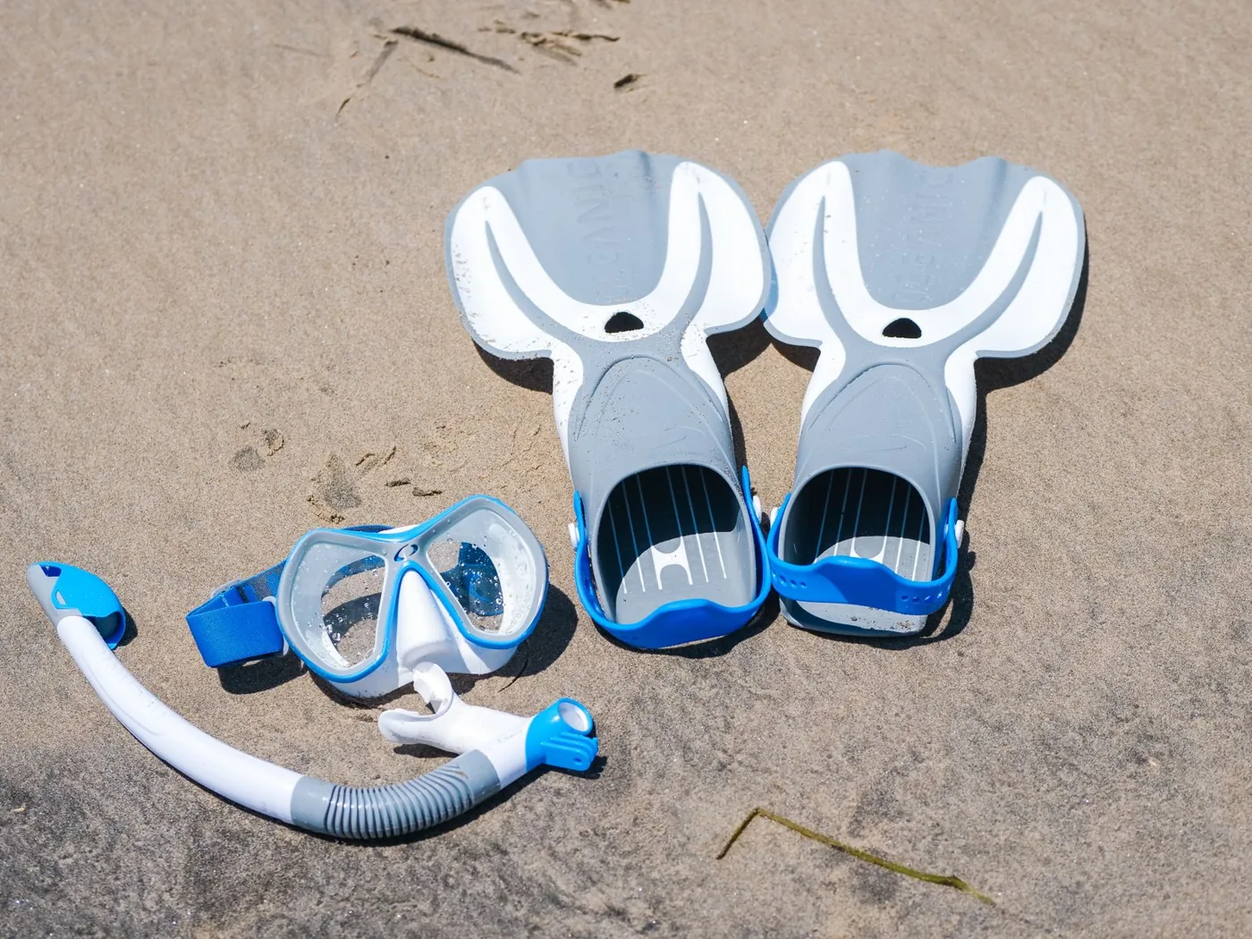 Mask, snorkel and fins arranged on sand