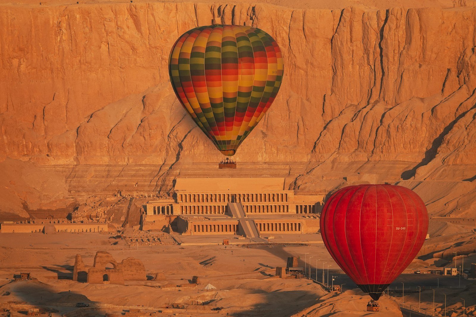 Two hot air balloons beside Hatshepsut Temple – 2-day Luxor tour from Hurghada