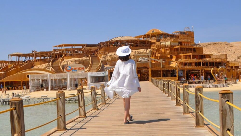 Orange Bay Hurghada Holzsteg mit türkisfarbenem Wasser und Inselgebäuden