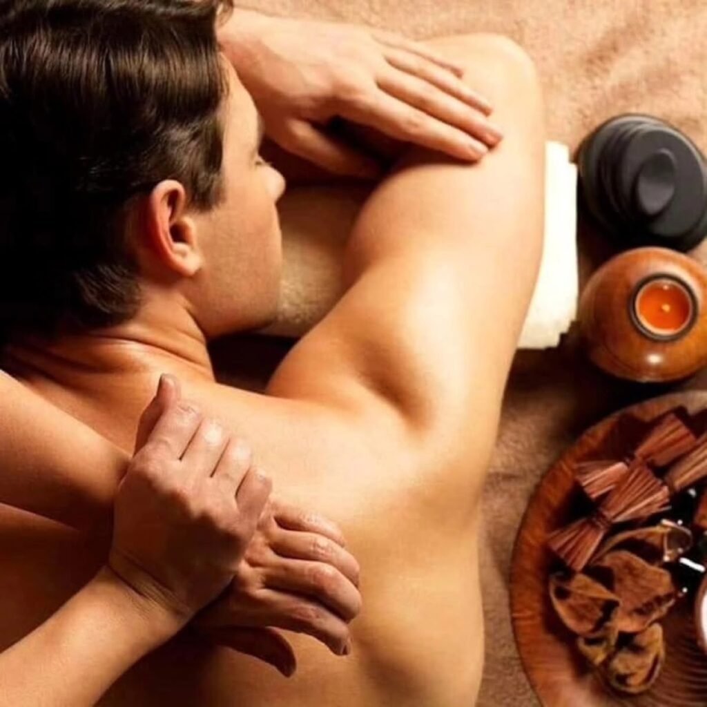 Rückenmassage eines Mannes mit Massagezubehör daneben – Symbolfoto